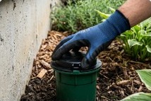 Gloved hand installing a termite bait station